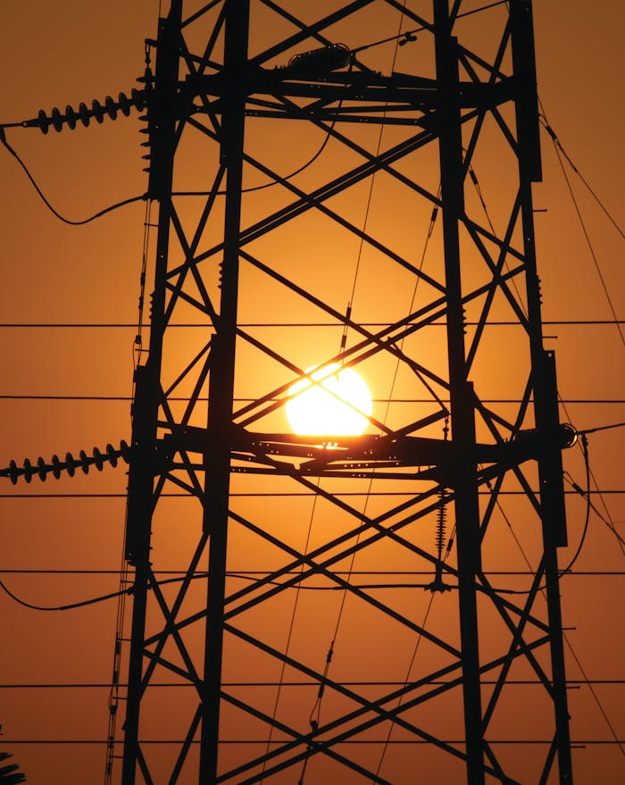 Silhouette of a powerline tower against a vibrant sunset in Vietnam, symbolizing energy and nature.